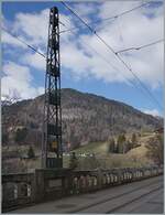 Der markante Fahrleitungsmast auf der Brücke bei Les Planches ist das eigentliche Sujet des Bildes, während im Hintergrund ein ASD Zug, bestehend aus einem BDe 4/4, einem Bt und einem