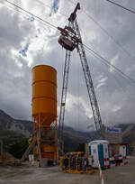 Unterhalb Alp Grüm werden die Alp Grüm der Berninabahn erneuert, daher gibt es eine Materialseilbahn von Alp Grüm hinab zu den Galerien, hier am 06.09.2021. So wird oben in Alp Grüm der Beton gemischt und dann mit der Seilbahn hinab gefahren. 

Die hier verwendete Bahn ist vom italienischen Seilbringungs-Spezialisten Seik (Truden). Der verwendete Wagen ist ein Seilkran vom Typ SFM 30/60.  In dem Seilkran befindet sich ein Verbrennungsmotor der das Hubwerk antreibt (dieser läuft nur bei der Hubbewegen) um wie hier den Betonkübel (hier unten und nicht im Bild) anzuheben und später wieder abzusenken. Die Hubkraft beträgt im Einzelzug 3t oder wie hier im Doppelzug mit dem Waagbalken 6t. Das Gesamtgewicht beträgt ca. 1t. Die Winde für das Zugseil kann nach Belieben (Bergseite – Talseite) platziert werden.