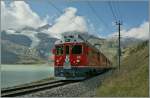 Im Schatten einer Wolke fahrt der Bernina ABe 4/4 N 53 mit einem Schwestertriewagen  und einem langen Regionalzug nach Tirano am Lac Bianco entlang und erreicht in Krze Ospizio Bernina.