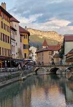 Impressionen aus der Altstadt von Annecy, der Fluß „Le Thiou“, vom See her kommend, die Altstadt und die Berge die den See umgeben, angestrahlt von der untergehender Sonne.